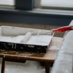 A paint roller and tray with white paint on a wooden table, indicating a renovation work. — Natural hazard zone disclosure re