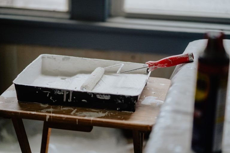 A paint roller and tray with white paint on a wooden table, indicating a renovation work. — Natural hazard zone disclosure re